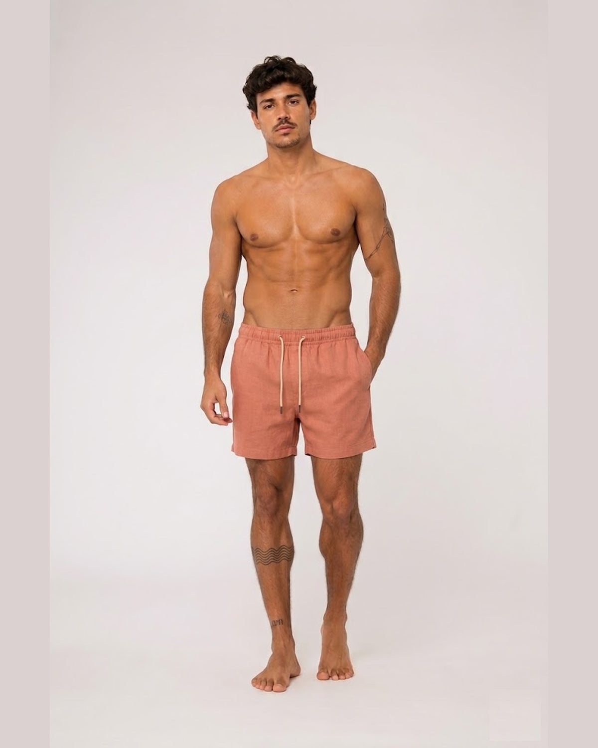 Modelo vestindo short de linho masculino Overbeach terracota, corpo inteiro de frente