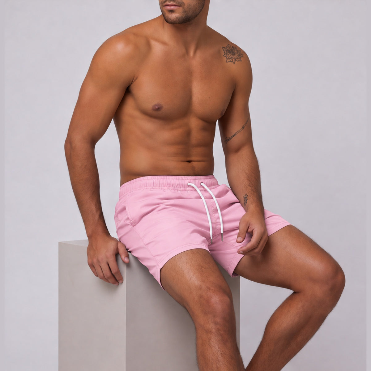 Modelo sentado usando short tactel masculino Overbeach rosa bebê, vista lateral do caimento