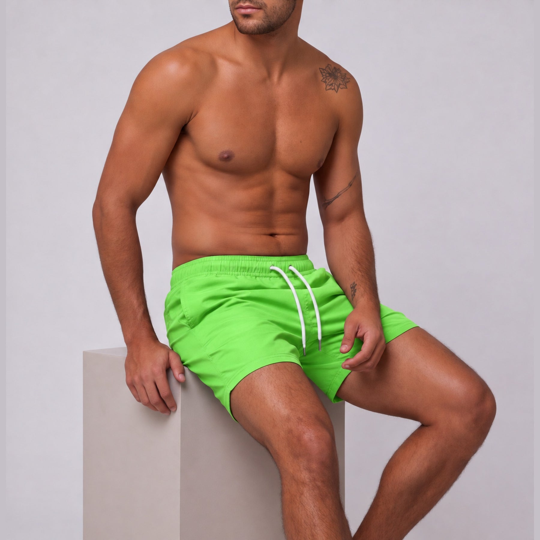 Modelo sentado usando short tactel masculino Overbeach verde neon, vista lateral do caimento