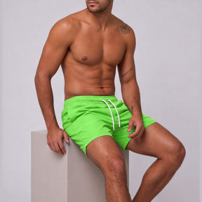 Modelo sentado usando short tactel masculino Overbeach verde neon, vista lateral do caimento